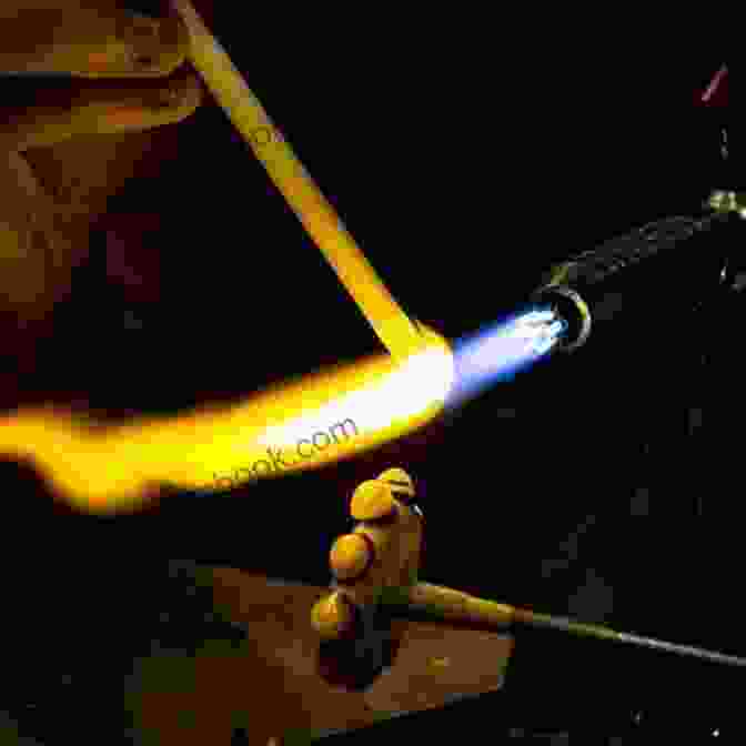 Close Up Image Of A Person Heating The End Of The Mandrel Rod With A Lampwork Torch. How To Make A Heart Lampwork Bead