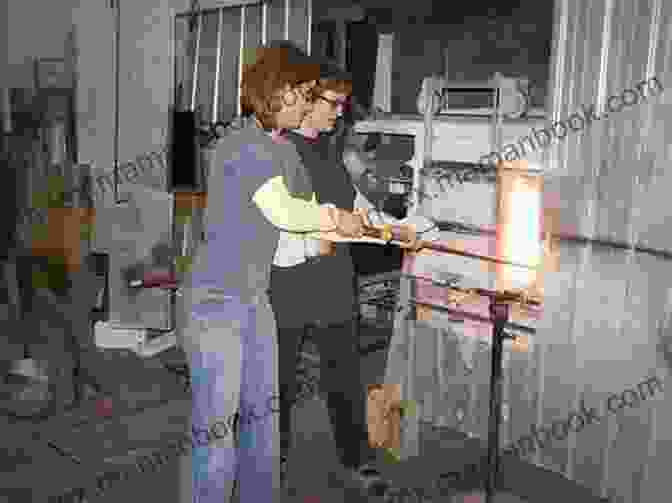 Image Of A Person Gathering Molten Glass From A Glass Rod And Wrapping It Around The Bead On The Mandrel Rod. How To Make A Heart Lampwork Bead